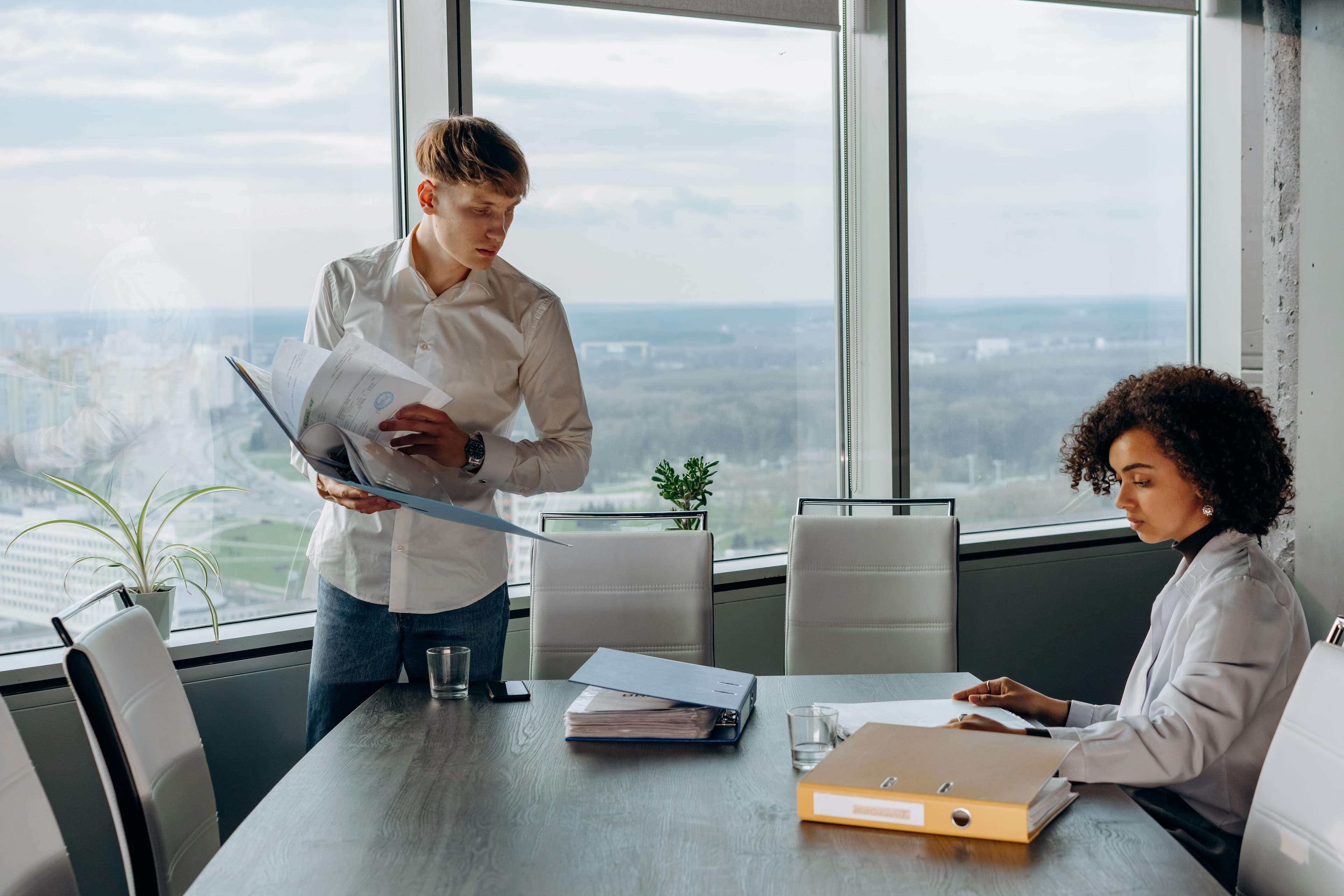 Two professionals in a modern office reviewing documents, emphasizing a business discussion about insurance coverage and risk management.